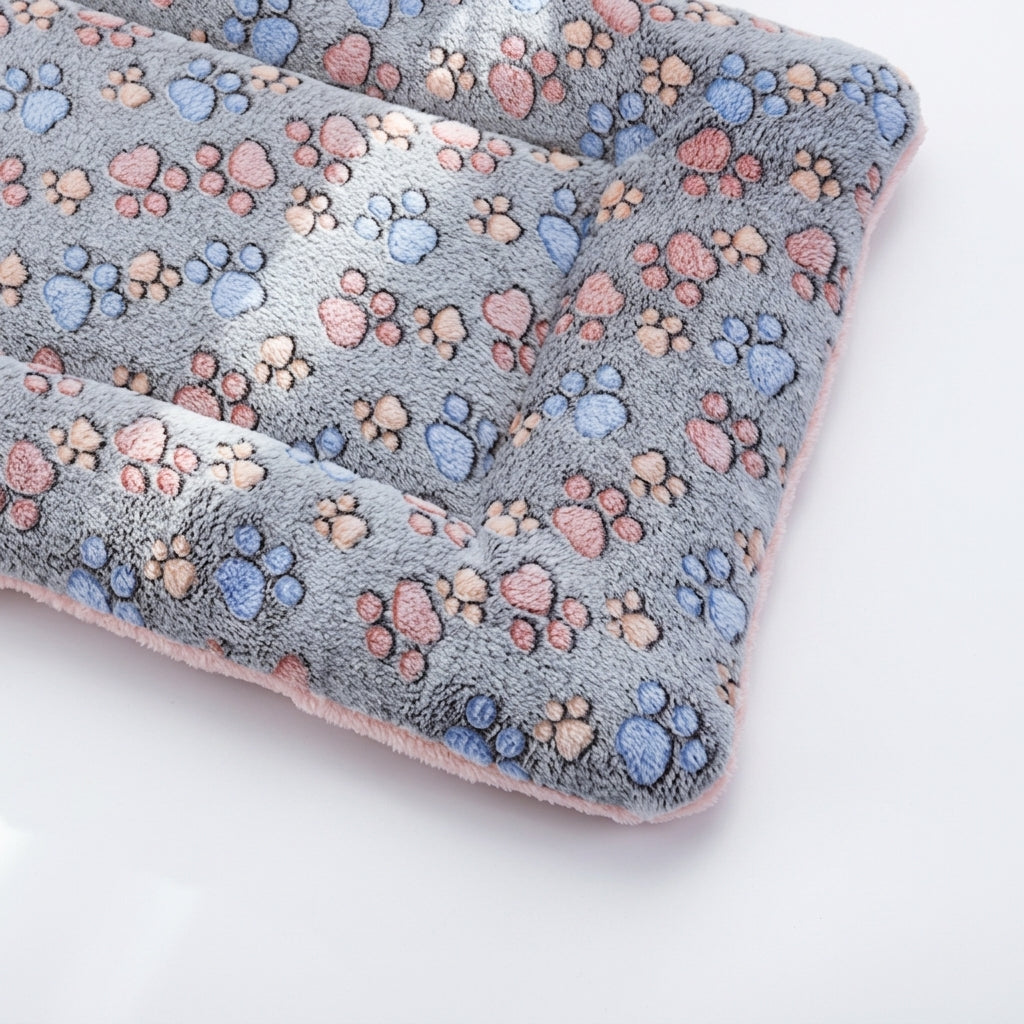 Padded fleece blanket bed in grey paws with pink, blue and peach paw prints and a pink underside, corner view