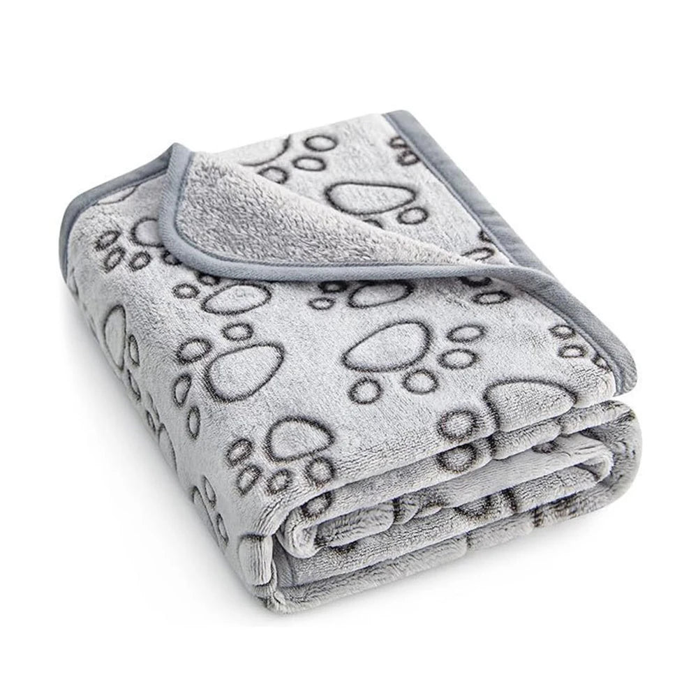 Blanket for dog beds and mats in light grey fleece with large dark grey outline paw prints, folded with a corner turned back