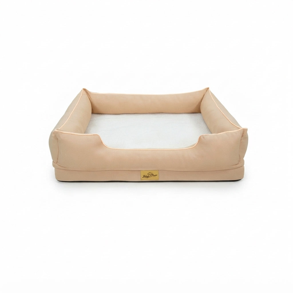 Calming dog bed in peach fabric with raised bolsters, a lower front edge and a white plush base