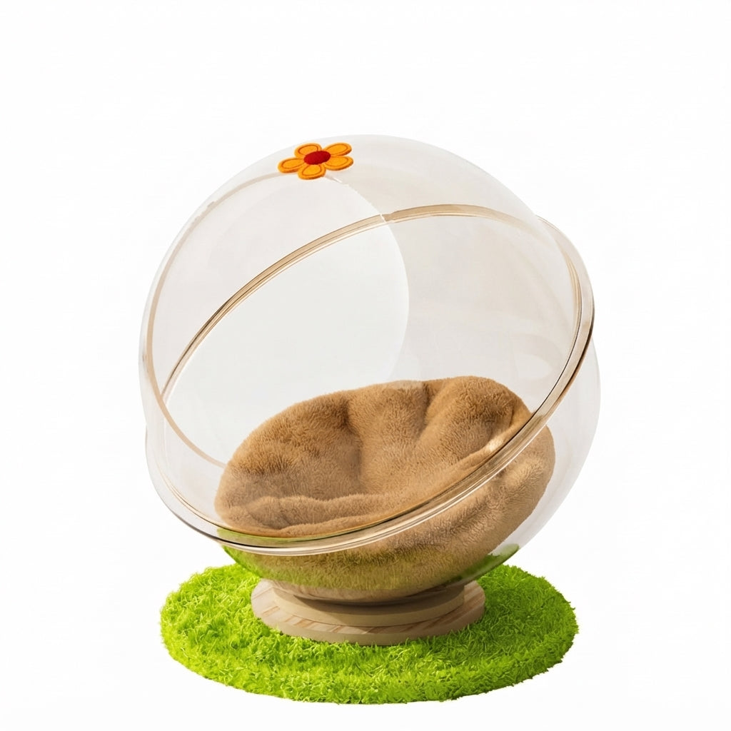 Cat cave bed made of a clear acrylic sphere with a camel plush cushion and a flower decal, on a wooden base over a green mat