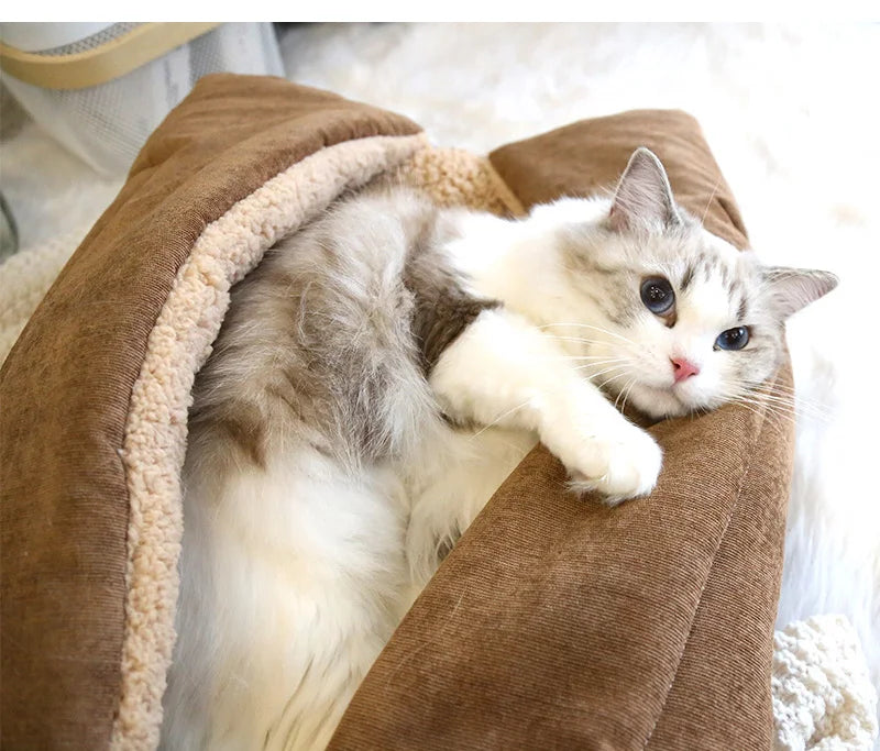 Fluffy grey and white cat curled up under the folded side of a beige cat cushion bed with a cream sherpa lining