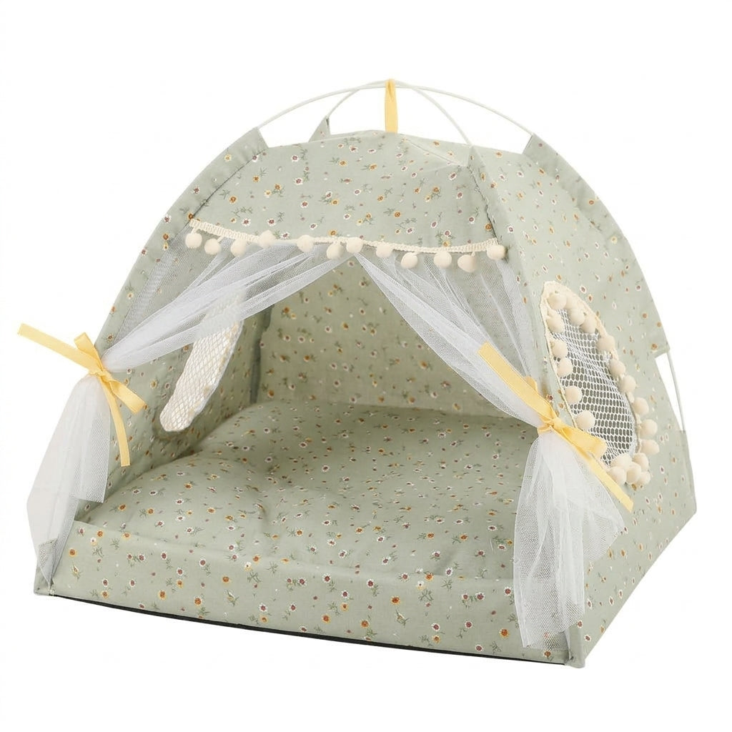 Cat tent bed in sage green with a tiny floral print, cream pompom trim, lace curtains tied with yellow ribbons