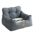 Dog travel bed in dark grey brushed fabric with a tufted backrest, a cream cushion and a black safety strap