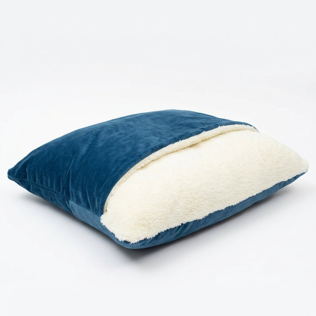 Dog bed cave in blue plush velvet with a cream sherpa pillow visible under the flap