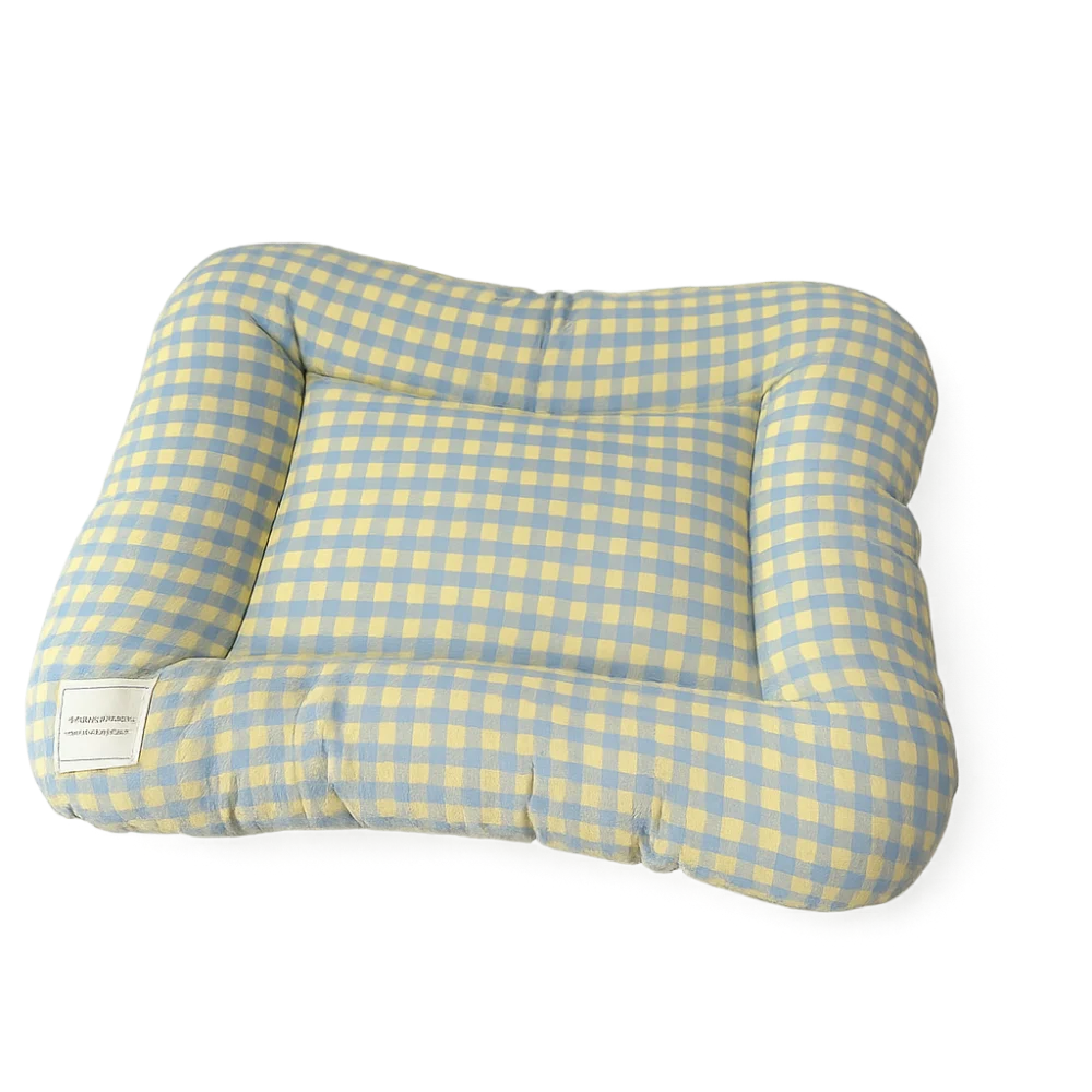 Dog bed cushion in blue and yellow gingham with a raised padded rim and a white label, on a black background