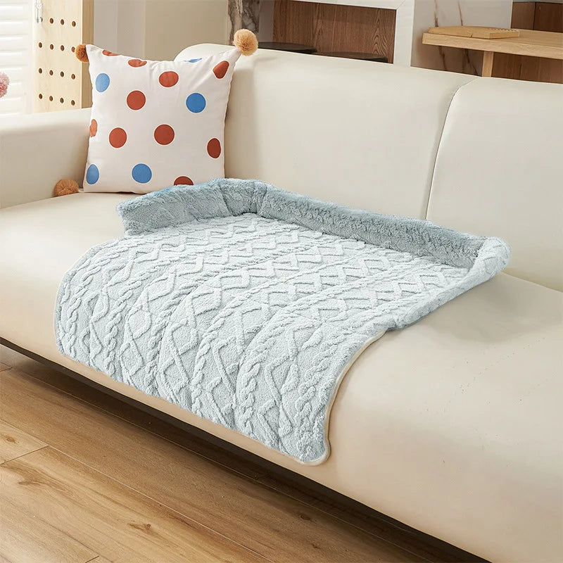 Blue cable knit sofa pad in a pale icy blue with a fluffy bolster, draped over the seat of a cream sofa