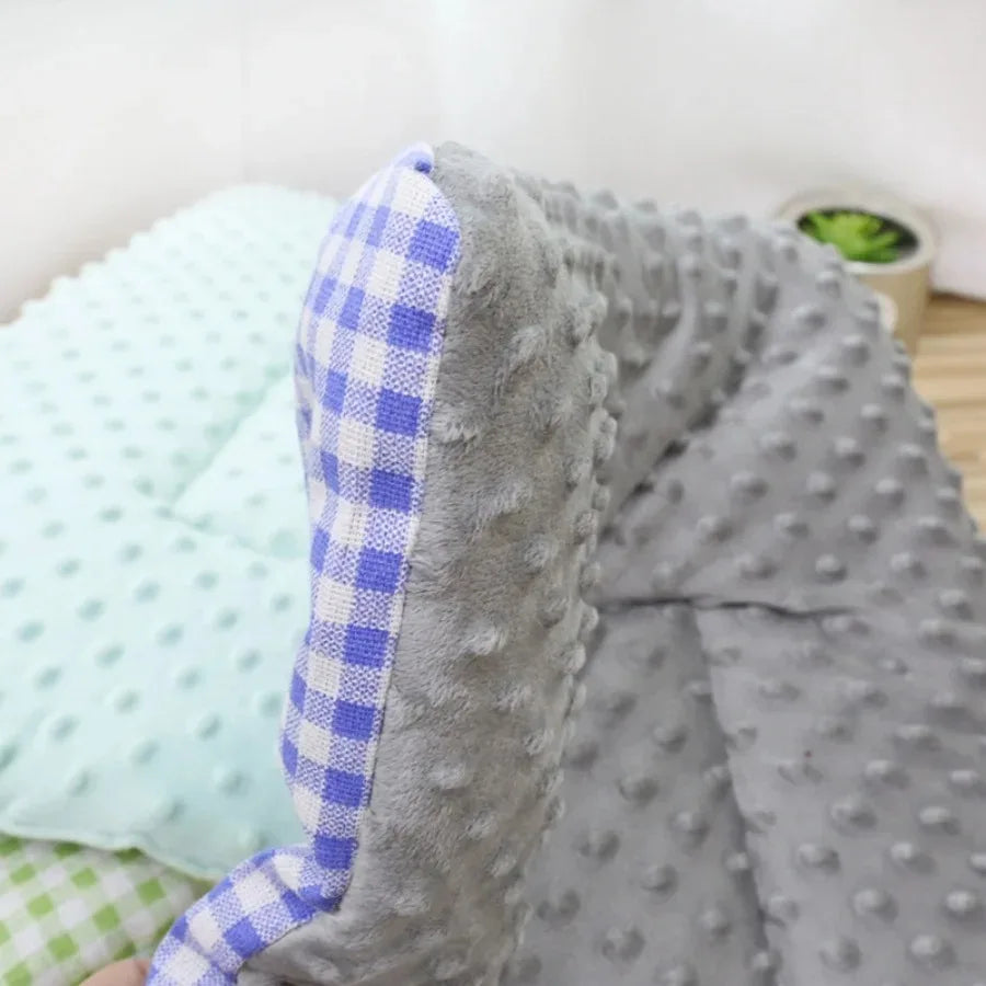 Close-up of the grey dotted plush pad with its blue and white gingham reverse, a mint pad behind it