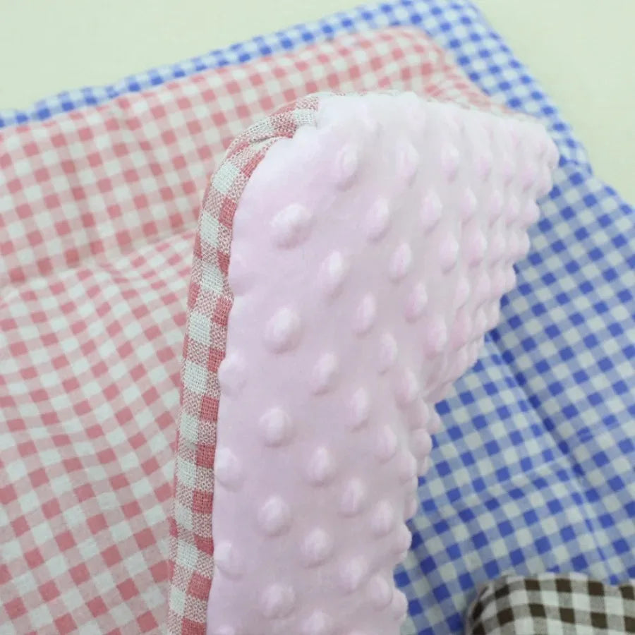 Close-up of the pink pad: pale pink dotted plush with a red and white gingham reverse, on blue gingham