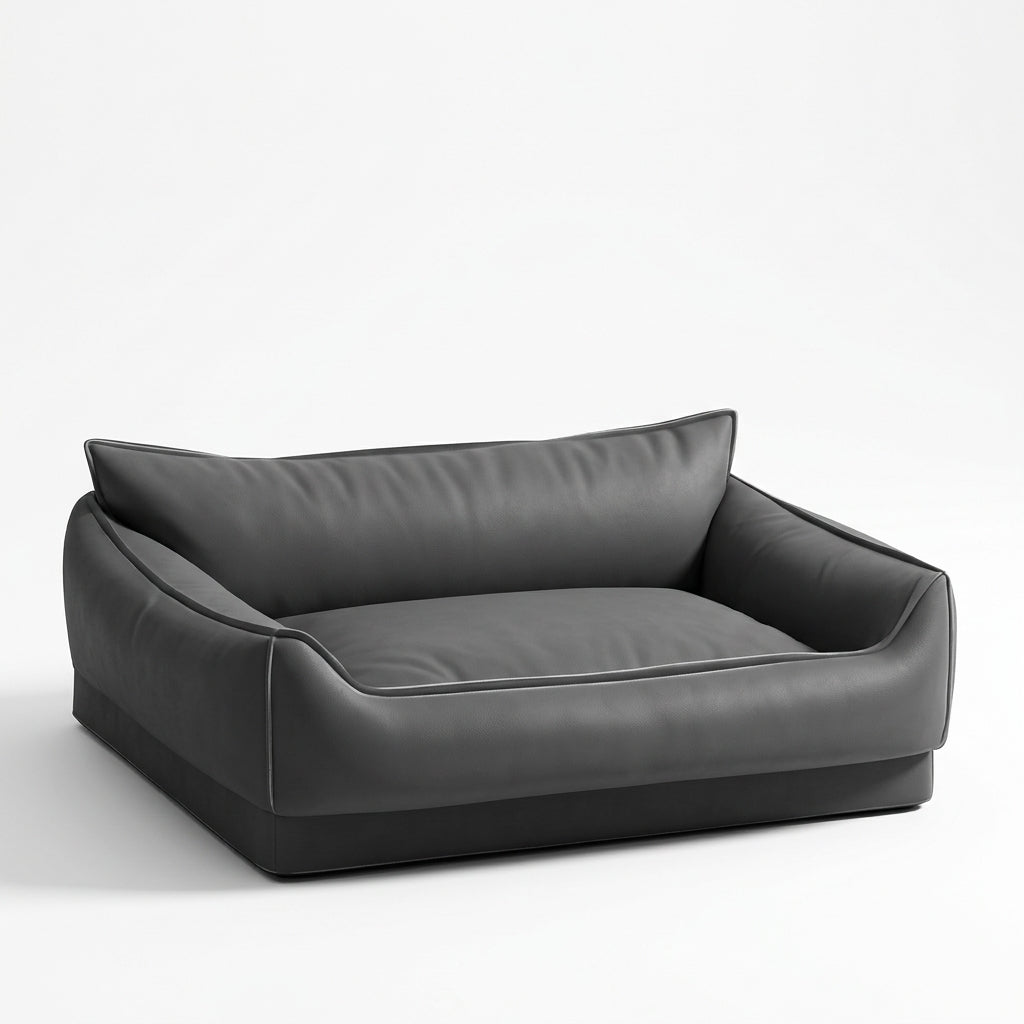 Dog bed sofa in black faux leather with a high cushioned back, low rounded sides, piped seams and a flat base