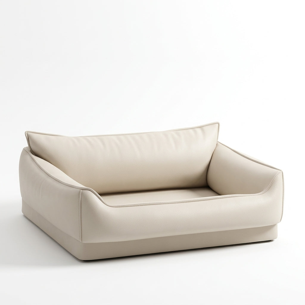 Dog bed sofa in cream faux leather with a high cushioned back, low rounded sides, piped seams and a flat base