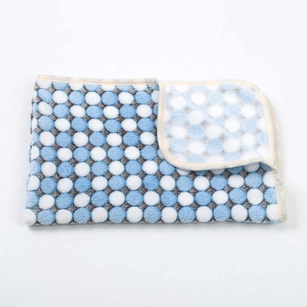 Folded fleece blanket with rows of blue and white dots on a grey ground and a cream edge