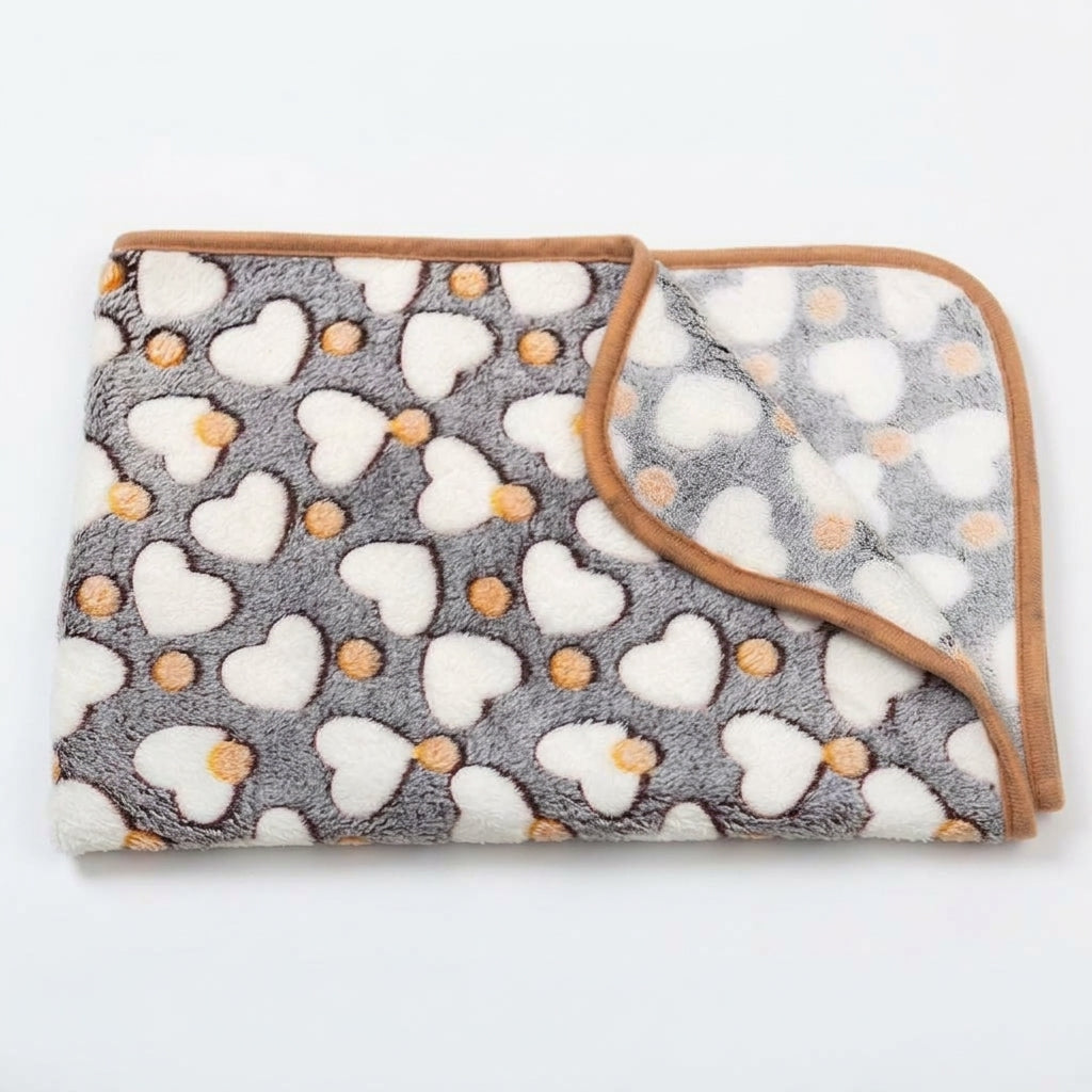 Folded grey fleece blanket with white hearts, small orange dots and a tan bound edge