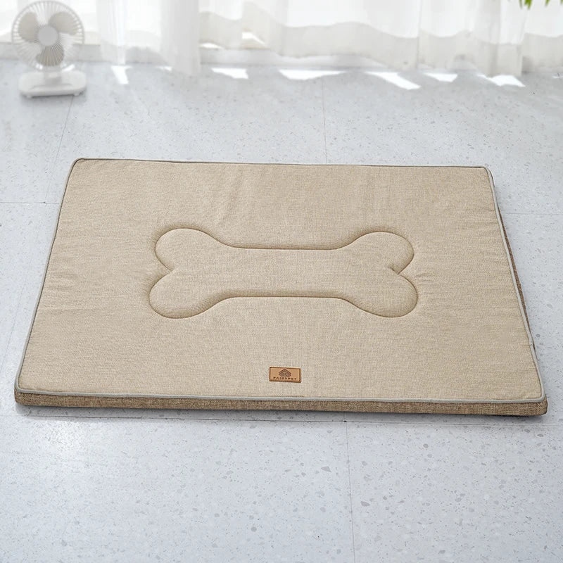 Tea brown linen mat lying flat on a speckled floor, with its quilted bone shape and grey piped edge