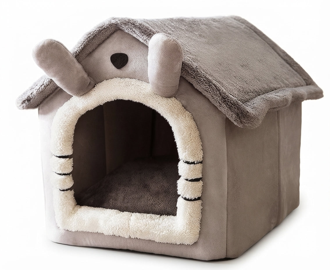 House-shaped dog bed in grey with two long ears on the roof, a cream plush doorway and whisker stitching