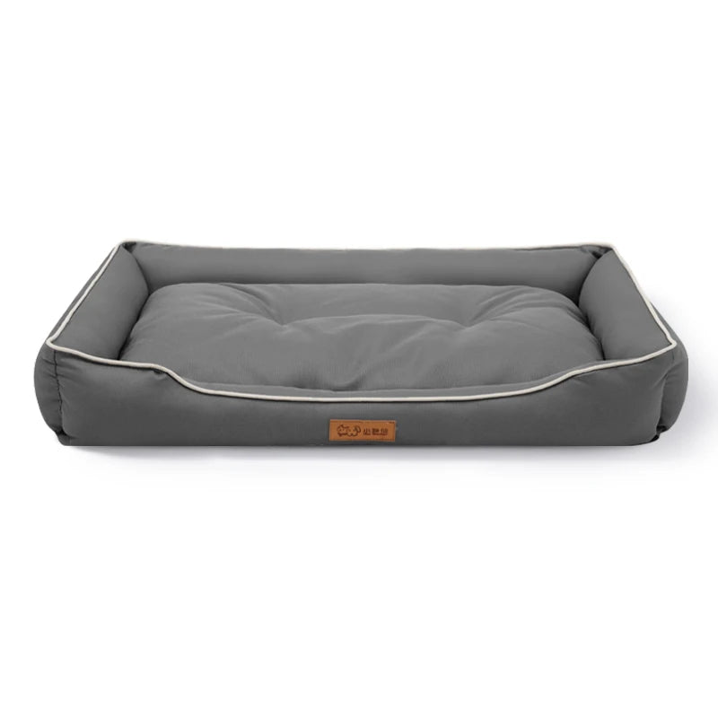 Dog settee bed in grey with white piping along the bolsters and a padded, tufted base