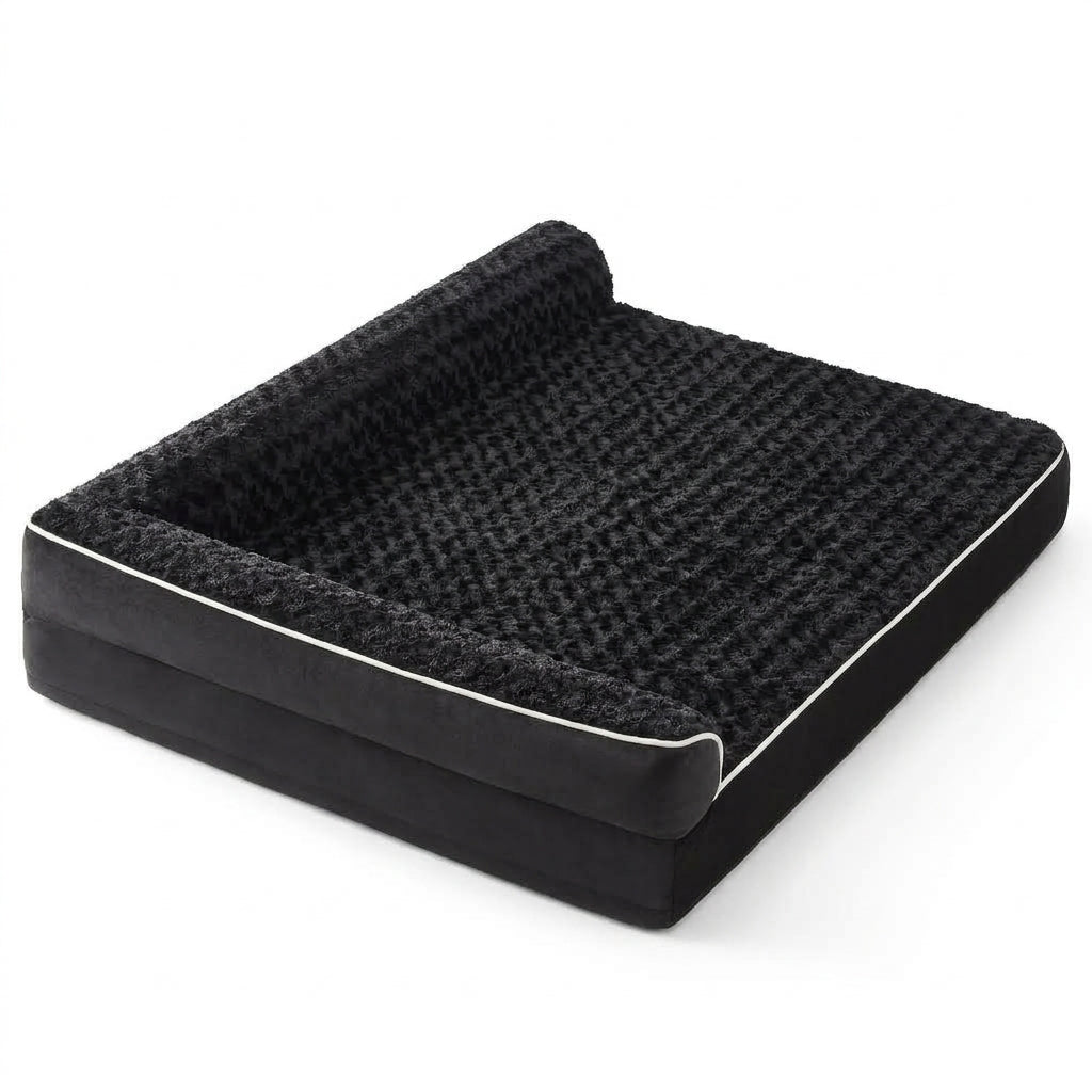 Black sofa-style dog bed with rose-textured plush, a bolster headrest along two sides and white piping