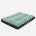 Flat dog bed in sage green wide-rib corduroy with a black fabric base, lying on a white floor