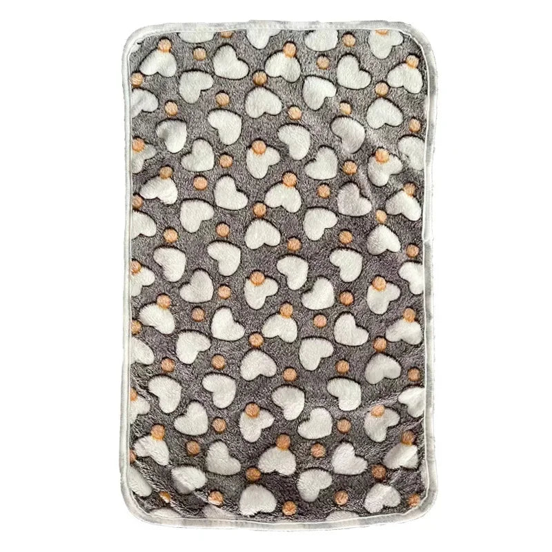 Grey fleece blanket for dog beds laid flat, printed with white hearts and small orange dots, with a pale edge