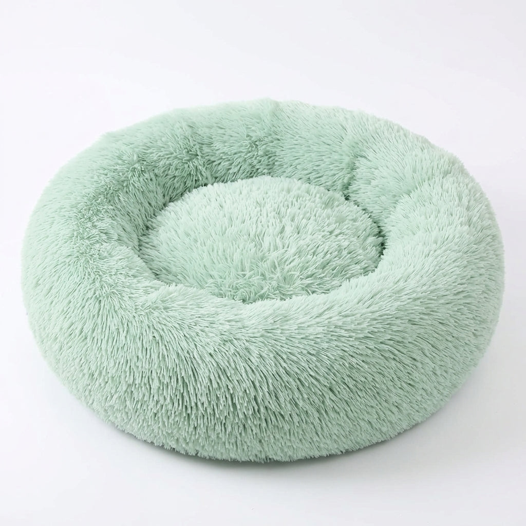 Fluffy bed for cats in light green shaggy faux fur, round with a raised padded rim and a sunken centre