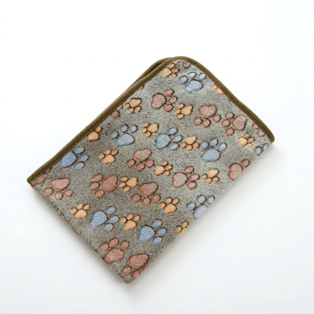 Folded coral fleece blanket in greyish brown with blue, peach and rose paw prints and a dark olive brown edge