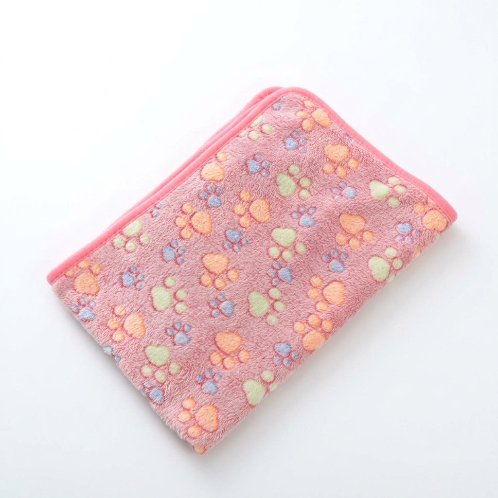 Folded pink coral fleece blanket with orange, green and lilac paw prints and a bright pink edge