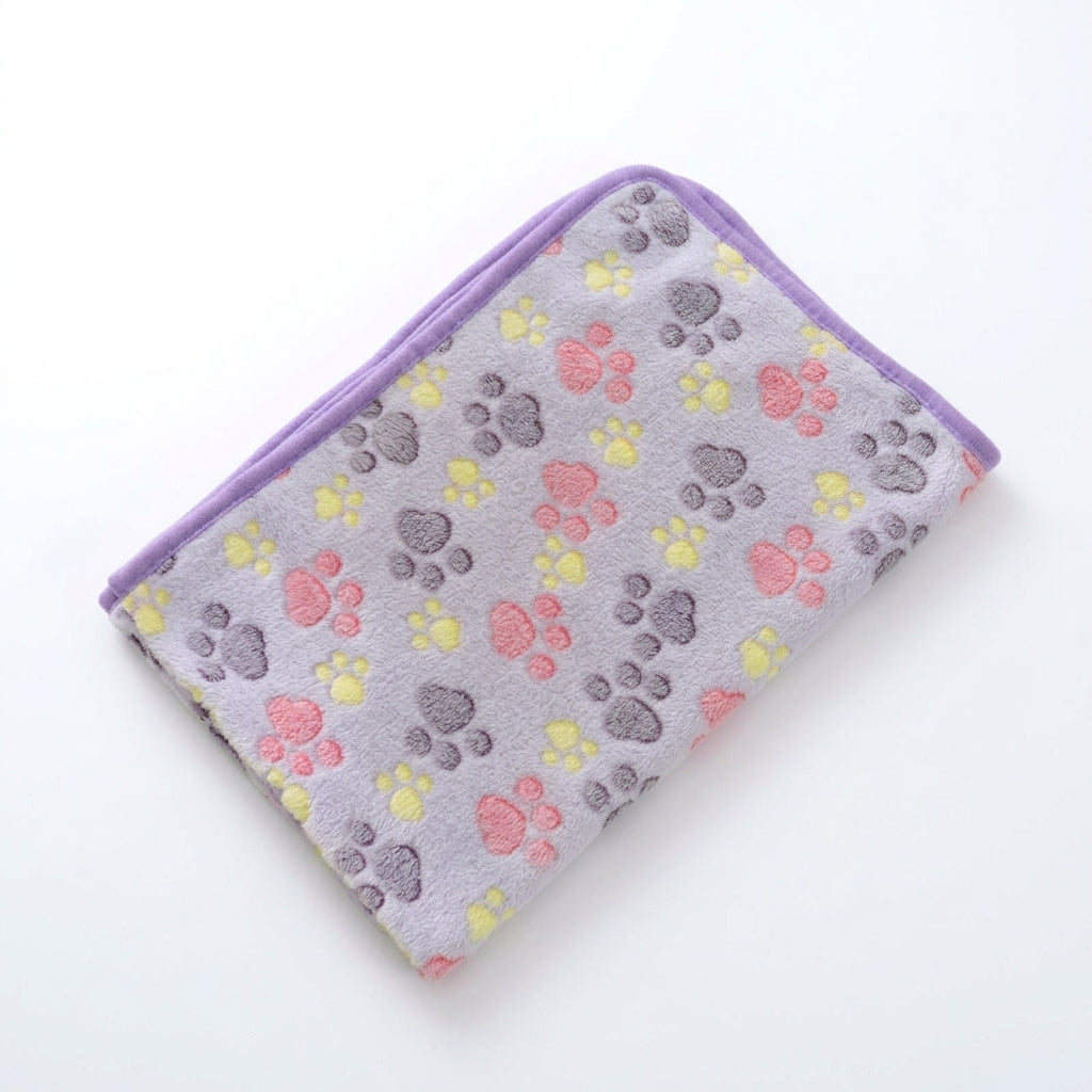 Folded coral fleece blanket in pale purple grey with pink, yellow and grey paw prints and a purple edge