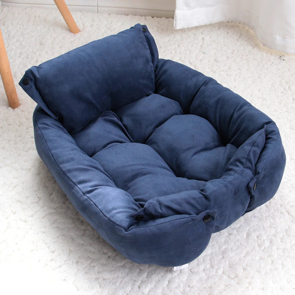 Blue foldable dog bed set up as a sofa, with a raised backrest and tufted seat, on a white shaggy rug