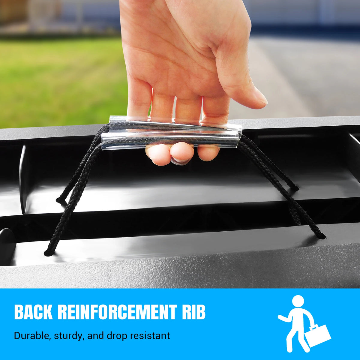 A person's hand holding the rope carry handle of the folded black dog ramp