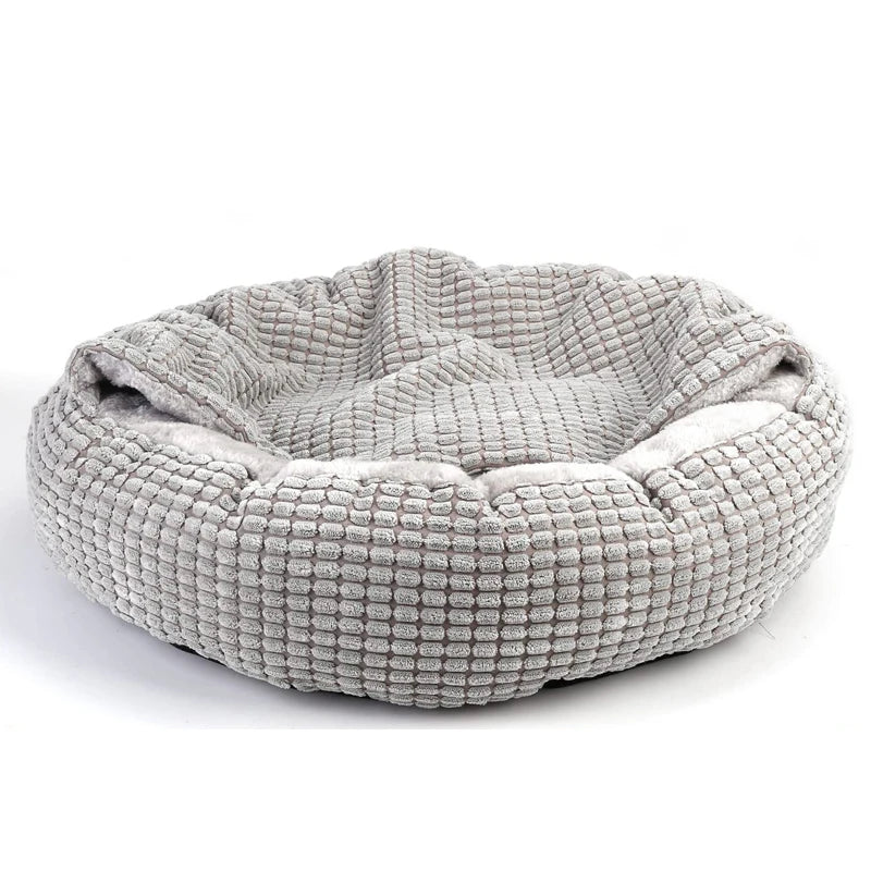 Hooded dog bed in grey, a round donut shape in grid-textured plush with the hood folded back over the rim
