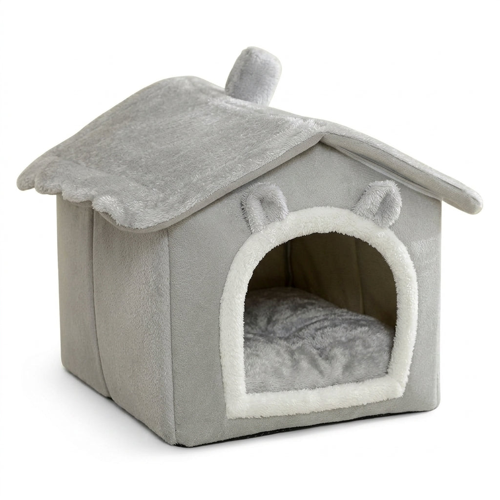 Grey house-shaped hooded pet bed with a plush roof and chimney, a white-trimmed arched doorway with ears and a grey cushion