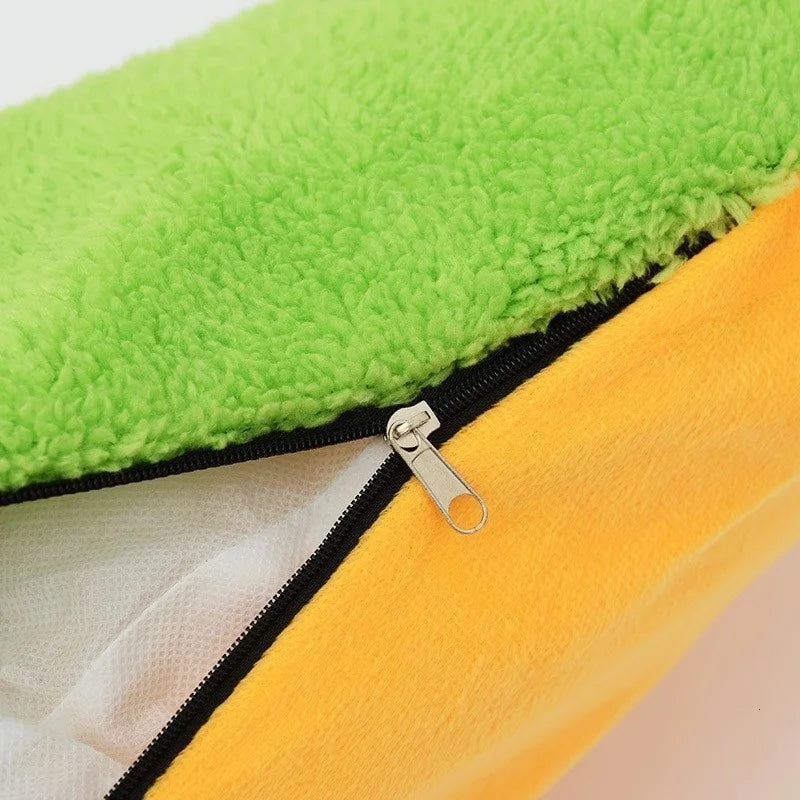 Close-up of a zip opening between green fleece and yellow-orange plush, with the white filling visible inside