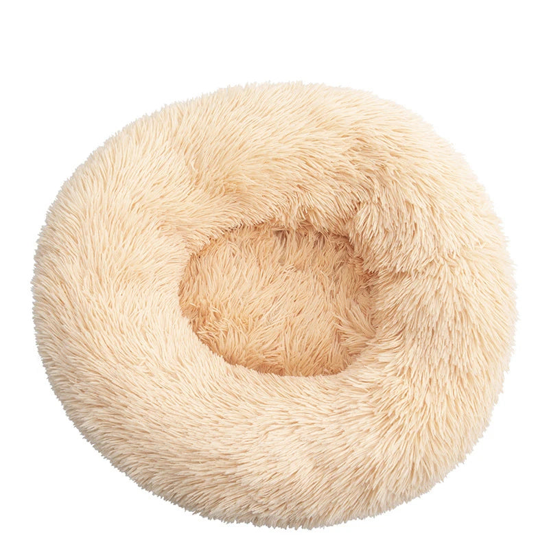 Round donut dog bed in cream shaggy plush, a pale apricot cream with a deep central hollow, seen from above