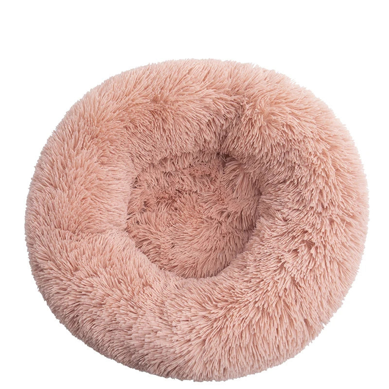 Round donut dog bed in dusty pink shaggy plush, a soft peachy pink with a deep central hollow, seen from above