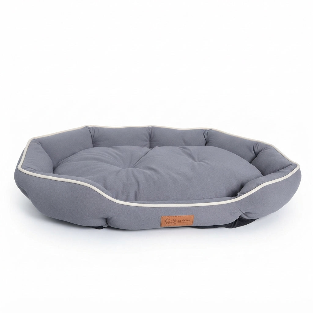 Octagonal dog bed in grey fabric with cream piping and a padded rim around a tufted cushion