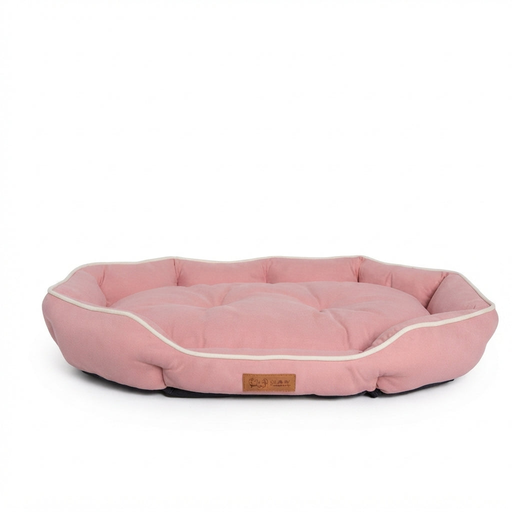 Octagonal dog bed in pink fabric with cream piping and a padded rim around a tufted cushion