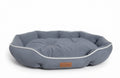 Small oval dog bed in blue-grey suede-look fabric with white piping and a tufted cushion