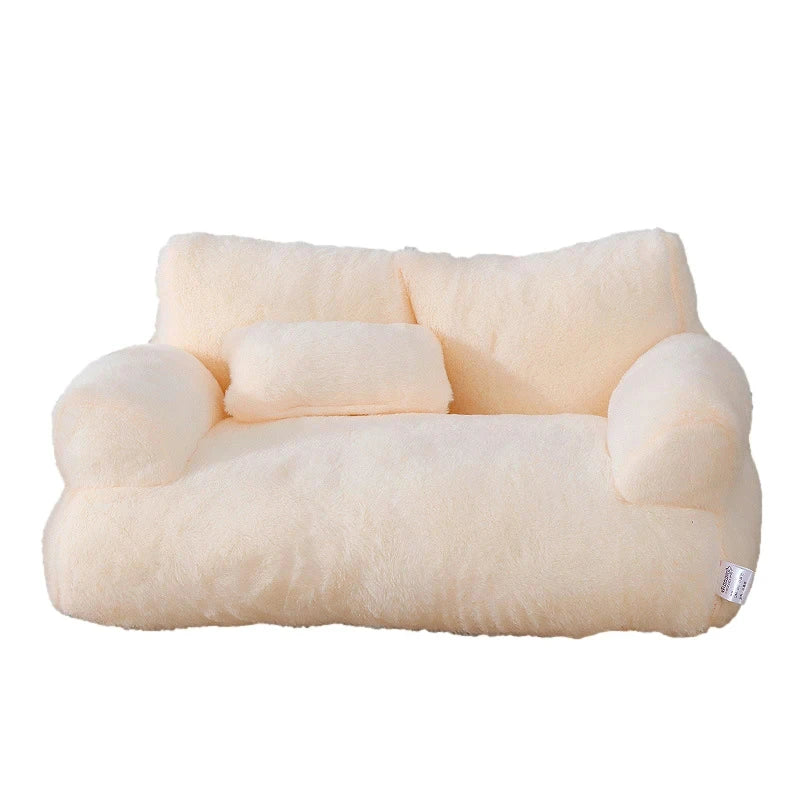 Plush two-seater sofa cat bed in cream faux fur with rounded armrests, a split backrest and a small pillow