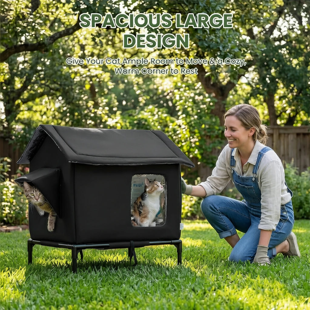 Black raised outdoor cat bed on a lawn with a tabby and a calico cat looking out, a woman kneeling beside it