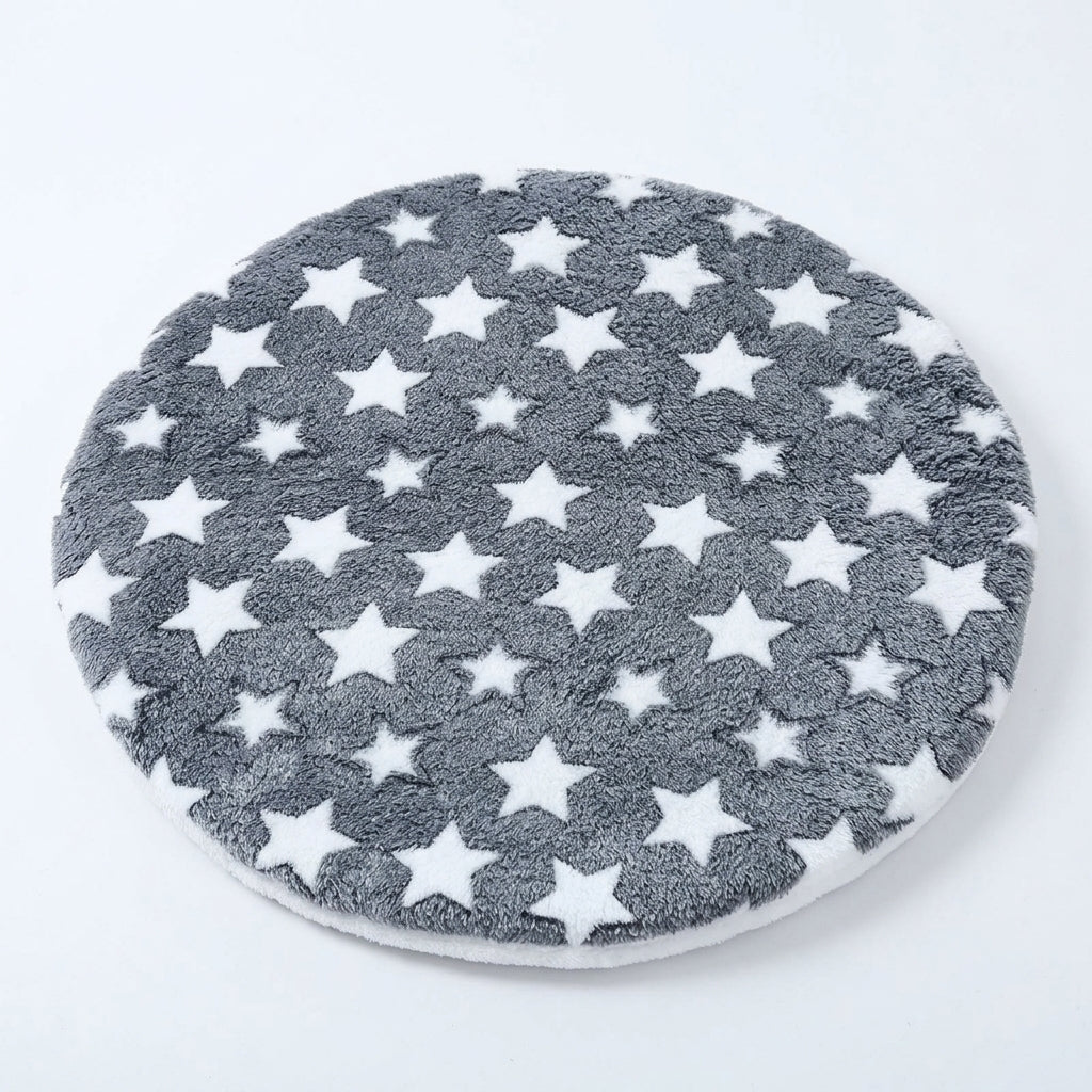 Round cat mat in dark grey plush with white stars, the cream fleece reverse side showing at the edge