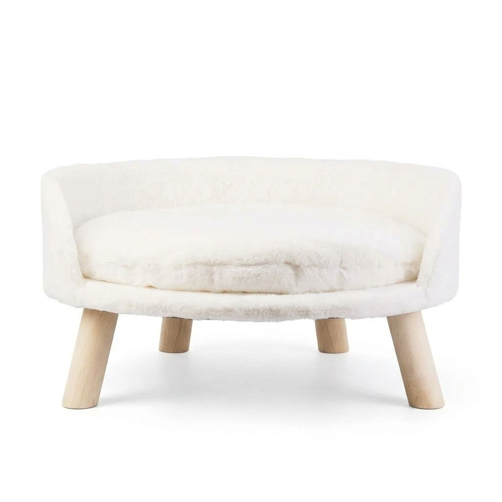 Round sofa bed for cats in cream plush with a curved backrest, a removable cushion and four wooden legs