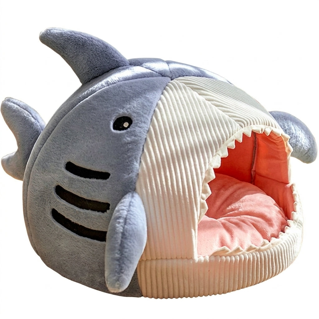 Shark cat bed cave in Blue plush with a cream corduroy front, zigzag teeth around the opening and a pink cushion