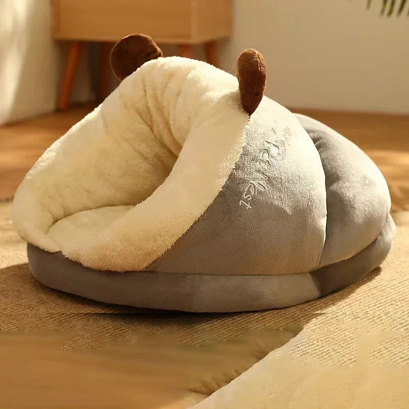 Slipper-shaped dog bed in grey with a cream plush lining and two brown antlers, on a rug in a sunlit room