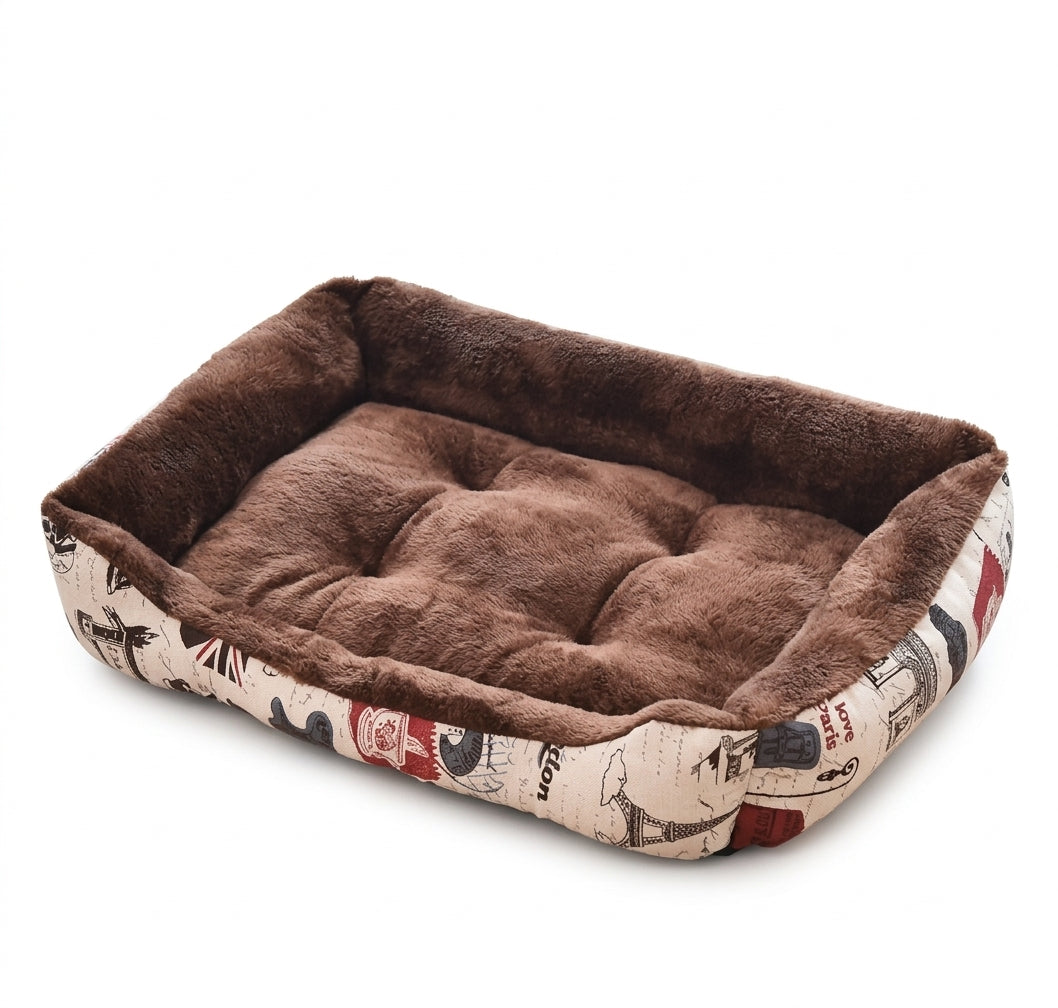 Rectangular dog bed in brown print: cream sides printed with Paris and London landmarks, and a brown plush lining