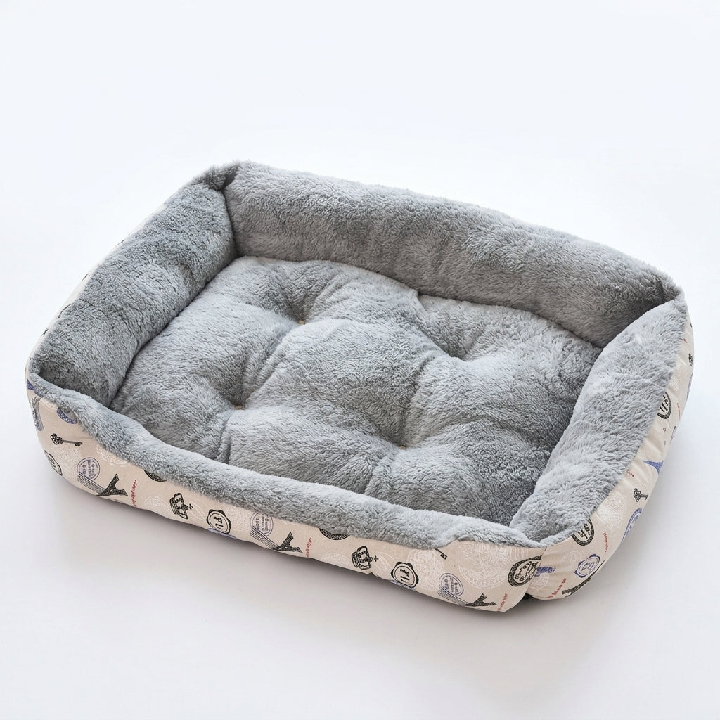 Rectangular dog bed in grey print: cream sides printed with Eiffel towers, crowns and stamps, and a grey plush lining
