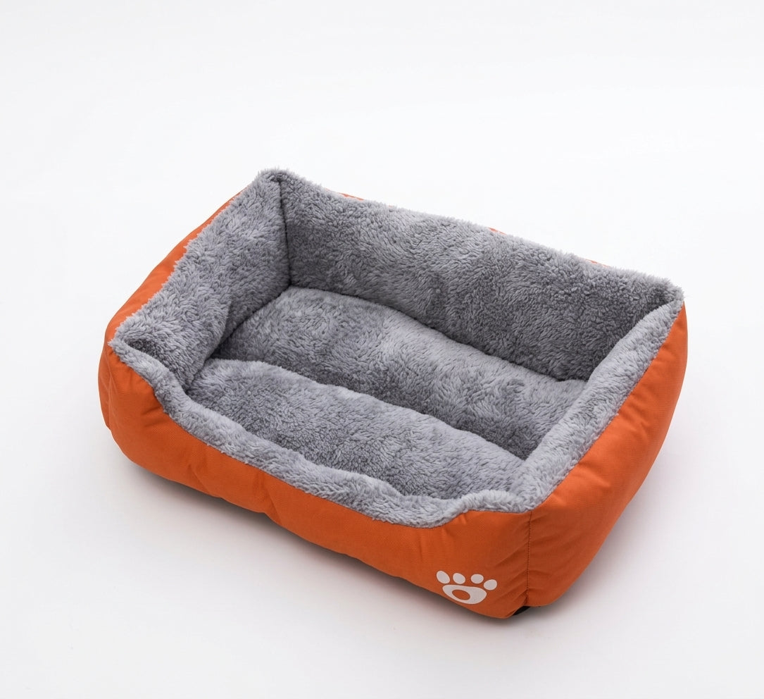 Rectangular dog bed in orange paw design: orange fabric sides with a white paw print and a grey plush lining