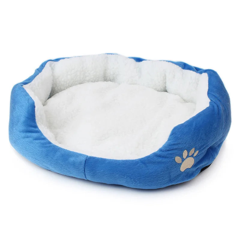 Oval pet bed in bright blue with a white fleece lining and a beige embroidered paw print on the side