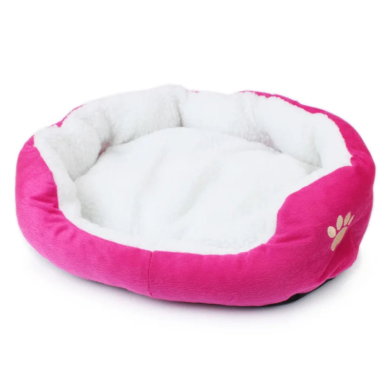 Oval pet bed in rose red, a bright magenta pink, with a white fleece lining and an embroidered paw print
