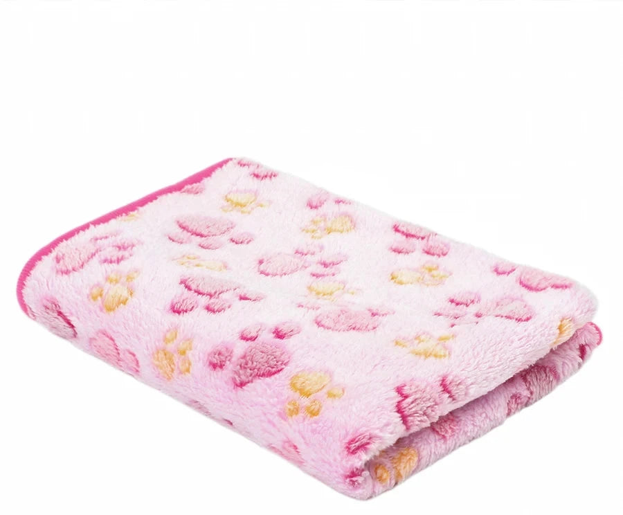 Folded pale pink coral fleece blanket with pink and yellow paw prints and a bright pink edge