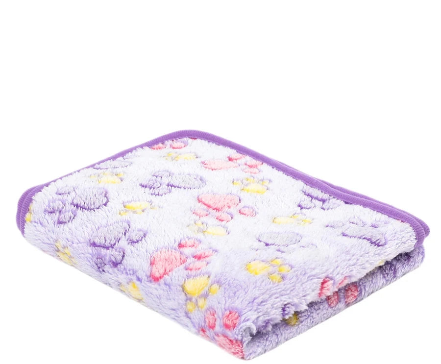 Folded lilac coral fleece blanket with purple footprints and pink and yellow paw prints, purple trim