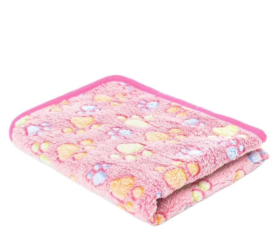 Folded coral fleece blanket in rose red footprints, a mid pink with orange, green and blue paw prints